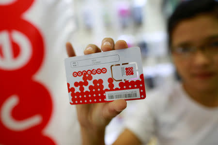 FILE PHOTO: A woman shows a SIM card from Qatar's Ooredoo after buying it from a phone shop in Yangon July 31, 2014.REUTERS/Soe Zeya Tun/File Photo