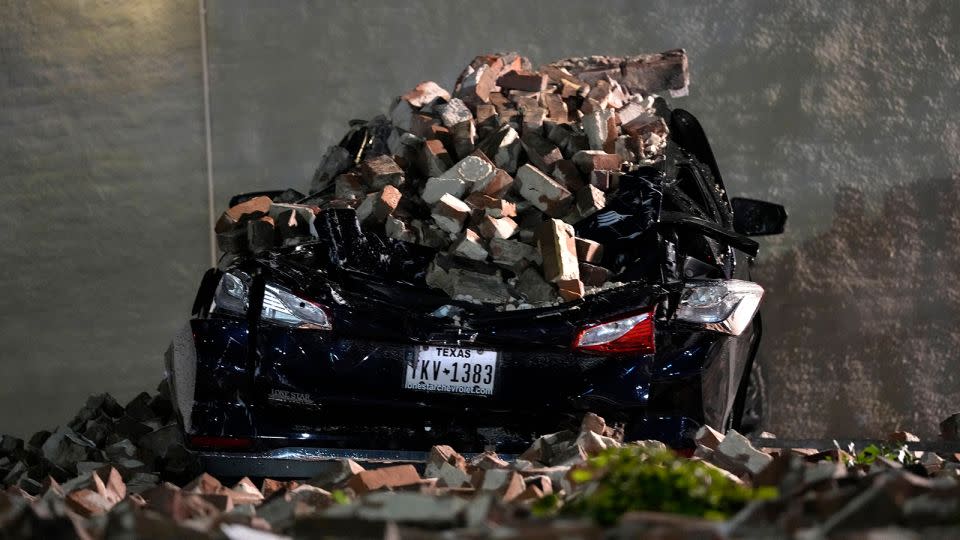 A car crushed by bricks from a fallen building wall sits in a downtown parking lot after a severe thunderstorm passed through Thursday in Houston. - David J. Phillip/AP