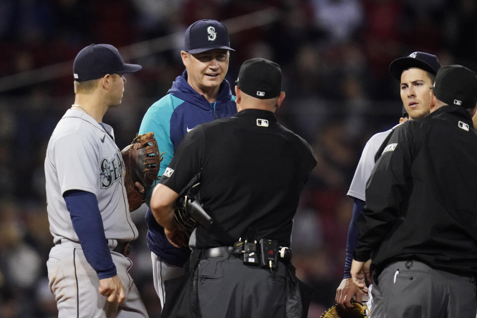 Seattle Mariners manager Scott Servais talks with umpires during during a pitching change in the sixth inning of the team's baseball game against the Boston Red Sox at Fenway Park, Thursday, May 19, 2022, in Boston. (AP Photo/Charles Krupa)