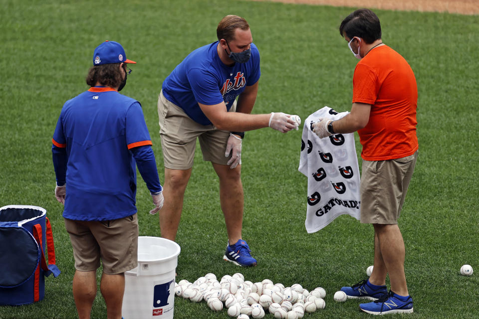 New York Mets team personnel clean baseballs after a workout at Citi Field in New York, Friday, July 3, 2020. Masks are being worn to prevent the spread of the coronavirus. (AP Photo/Adam Hunger)