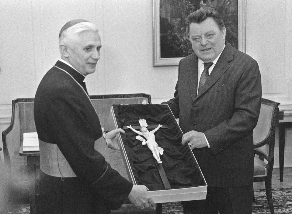 FILE - Bavarian State Governor Franz Joseph Strauss, right, gives a crucifix as a farewell gift to Cardinal Joseph Ratzinger, who will leave to head the Congregation for the Doctrine of the Faith at the Vatican, during his official farewell visit at the State Chancellery in Munich, Germany, on Feb. 12, 1982. Cardinal Ratzinger went on to become Pope Benedict XVI. Pope Emeritus Benedict XVI, the German theologian who will be remembered as the first pope in 600 years to resign, has died, the Vatican announced Saturday. He was 95. (AP Photo/Claus Hampel, File)