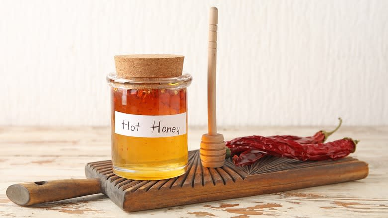 Homemade hot honey in jar with chiles and honey stick