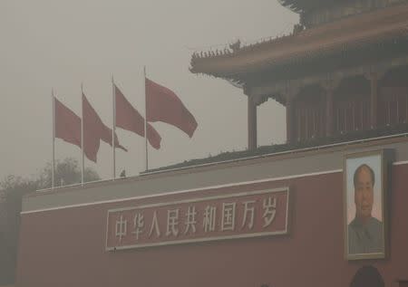 A security guard stands guard on the Tiananmen Gate where the giant portrait of China's late Chairman Mao Zedong is hung, during a heavily polluted day in Beijing, November 30, 2015. REUTERS/Kim Kyung-Hoon