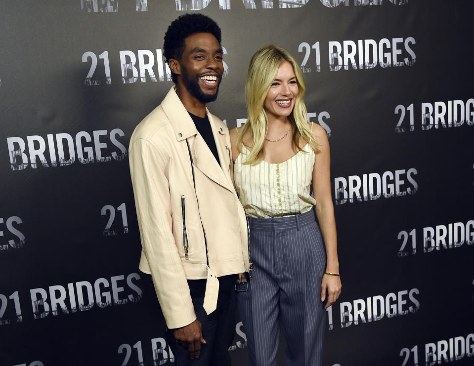 Chadwick Boseman, left, and Sienna Miller, cast members in "21 Bridges," pose together during a photo call for the film at the Four Seasons Hotel, Saturday, Nov. 9, 2019, in Los Angeles. (Photo by Chris Pizzello/Invision/AP)