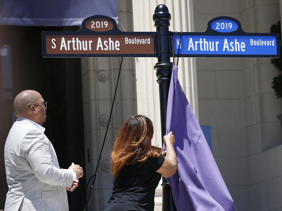 David O. Harris, Jr., Arthur Ashe's nephew, watches Richmond Councilwoman Kimberly B. Gray unveil one of the Arthur Ashe Boulevard signs during a renaming the boulevard ceremony at the Virginia Museum of History and Culture in Richmond, Va., Saturday, June 22, 2019. (Alexa Welch Edlund/Richmond Times-Dispatch via AP)