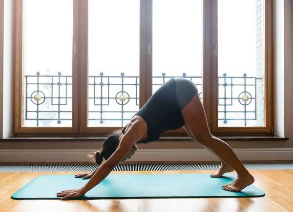 Woman doing yoga in front of floor to ceiling windows