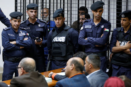 The accused stand behind police officers during their trail for staging an attack on December 2016 on a Crusader castle in Karak, at the State Security Court, in Amman, Jordan November 13, 2018. REUTERS/Muhammad Hamed