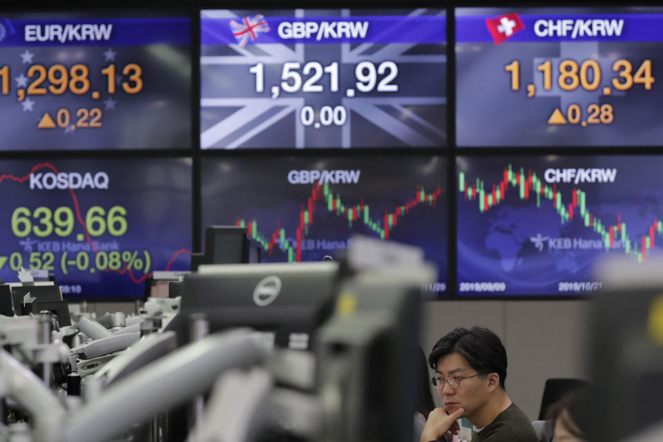 A currency trader watches computer monitors near the screens showing the foreign exchange rates at the foreign exchange dealing room in Seoul, South Korea, Friday, Nov. 29, 2019. Shares extended losses in Asia on Friday after Japan and South Korea reported weak manufacturing data that suggest a worsening toll from trade tensions. (AP Photo/Lee Jin-man)