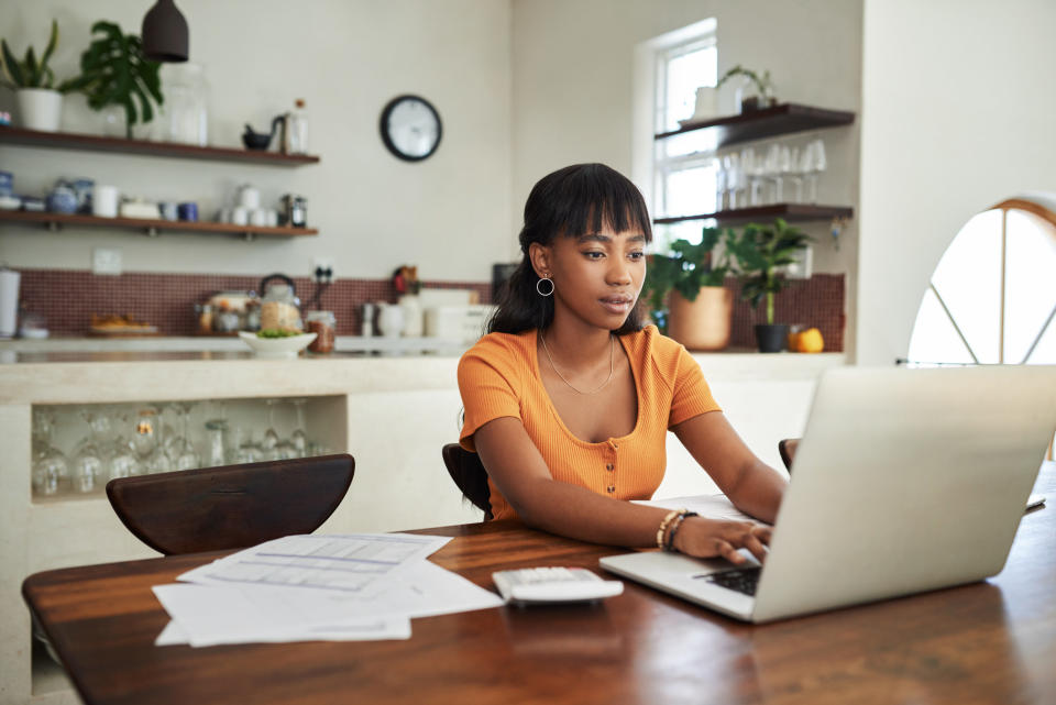 young woman sitting with her laptop and paperwork at home