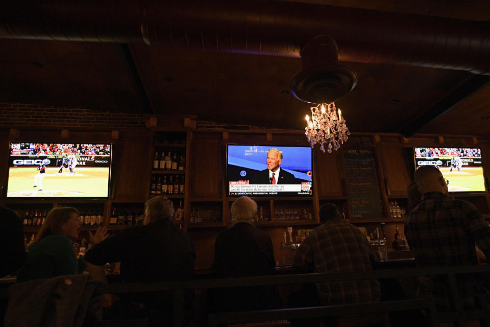 Patrons at the Hawk 'n' Dove sit in front of television screens televising Game 4 of the NLCS between Washington Nationals and the St. Louis Cardinals and the Democratic debate, Tuesday, Oct. 15, 2019, in Washington. (AP Photo/Nick Wass)