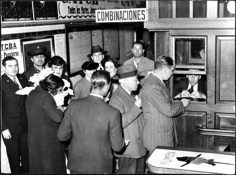 Usuarios haciendo fila para comprar boletos. Se observan tipografía y señalética de la Corporación de Transportes de Buenos Aires (creada en 1936), y publicidad de la época.
1940. Archivo General de la Nación.
