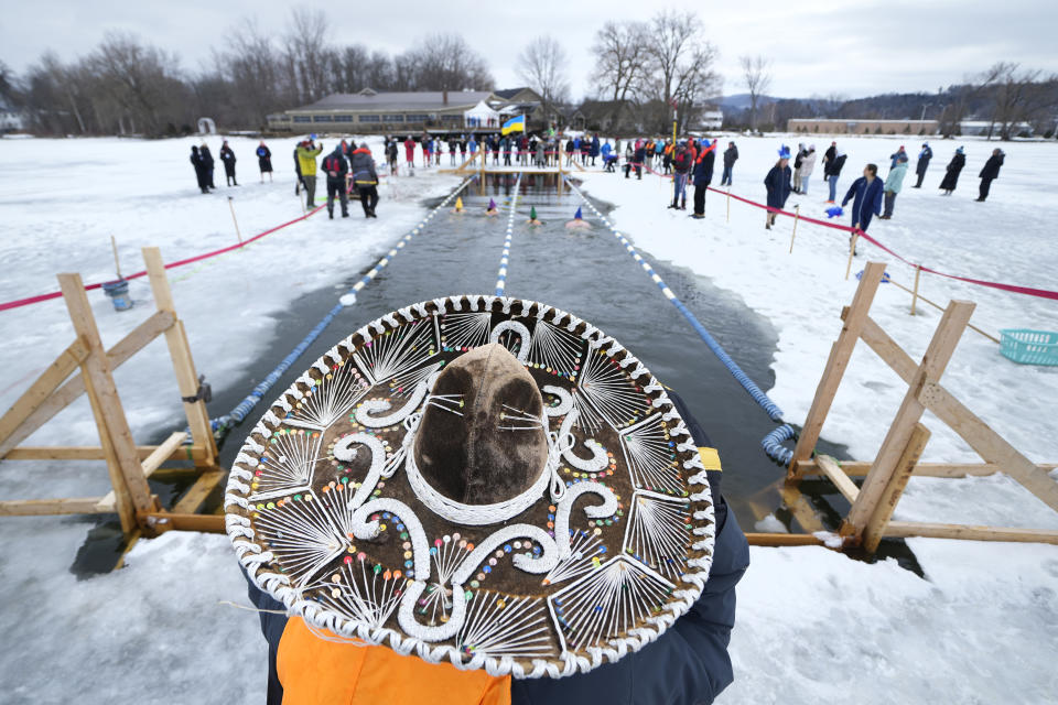 Organizer Phil White watches swimmers while wearing a sombrero during the 25 meter hat competition during the winter swimming festival on frozen Lake Memphremagog, Friday, Feb. 23, 2024, in Newport, Vermont. (AP Photo/Charles Krupa)