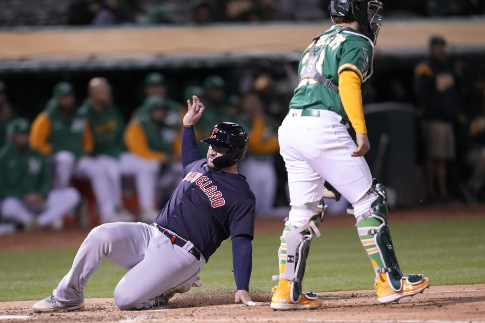 Cleveland Guardians' Mike Zunino, left, slides home to score next to Oakland Athletics catcher Shea Langeliers during the sixth inning of a baseball game in Oakland, Calif., Monday, April 3, 2023. (AP Photo/Jeff Chiu)