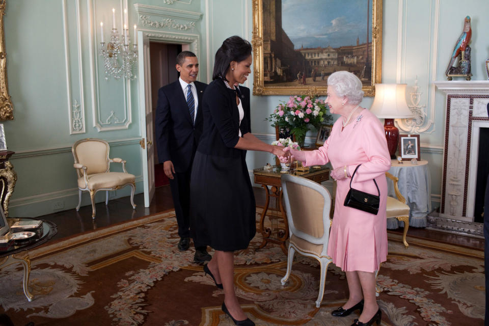 First lady Michelle Obama shakes hands with Queen Elizabeth II, with President Barack Obama following his wife.