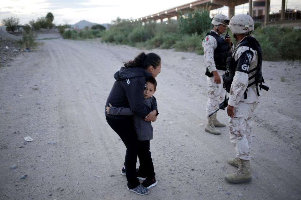 Guatemalan migrant Ledy Pérez embraces her son Anthony as she pleads with Mexican armed police