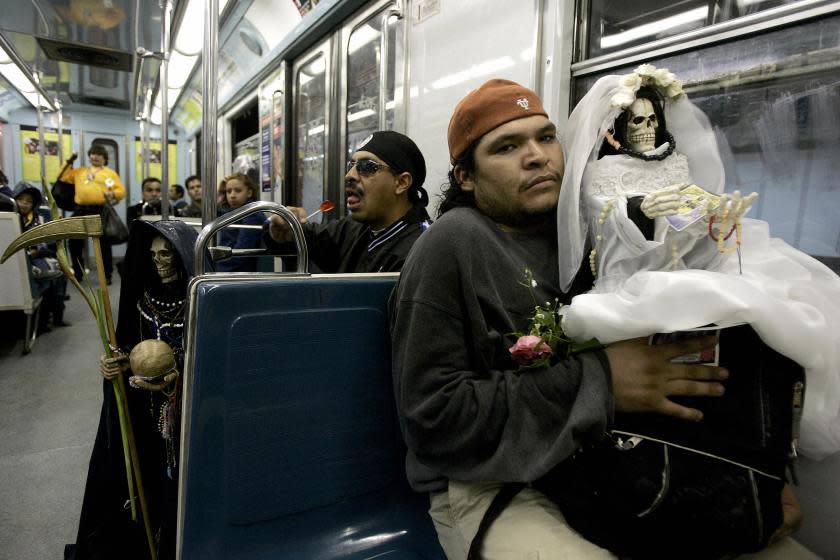 Men carrying effigies take the metro home after paying their respects to the Santa Muerte at the Romero's house altar to the deity in the infamous Tepito neighborhood in Mexico City