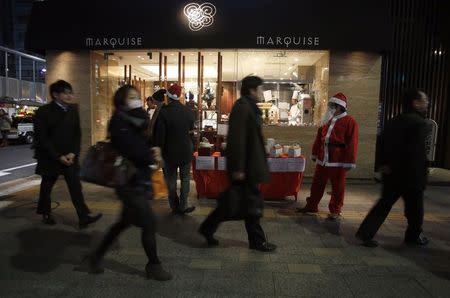 A man dressed as Santa Claus promotes Christmas cakes to pedestrians outside a pastry store at Tokyo's Ginza shopping street December 25, 2014. REUTERS/Yuya Shino