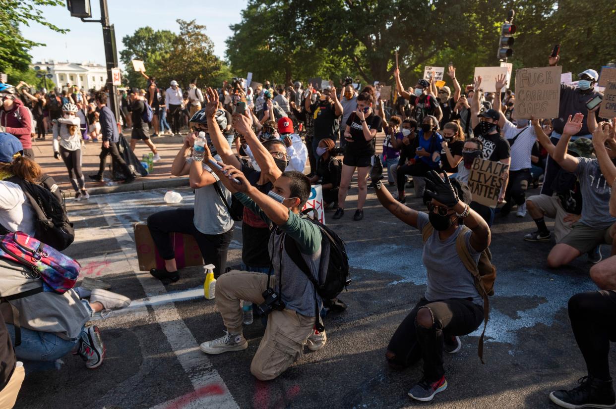 Protestors take a knee and raise their hands as they face riot police near the White House on June 1 as demonstrations against George Floyd's death continue.