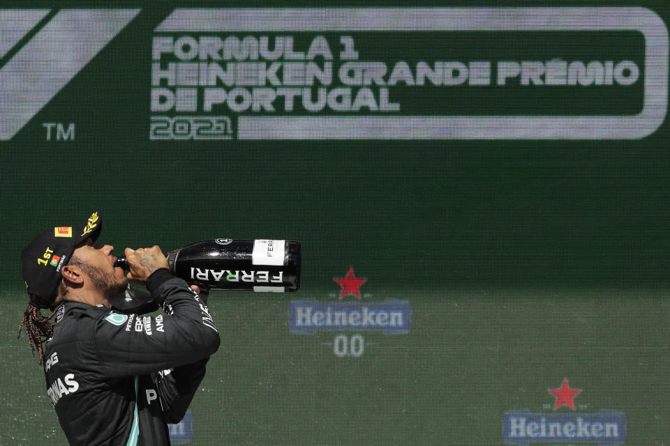 Lewis Hamilton bebe champaña al celebrar su victoria en el Gran Premio de Portugal, el domingo 2 de mayo de 2021, en el circuito de Algarve. (AP Foto/Manu Fernández)