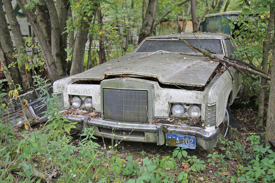 <p>The leaves and moss are accumulating around this 1977 Lincoln Continental Town Coupe ’s once-hidden headlights. It’s the same elsewhere on the car, and it won’t do it any favors in the long run.</p><p>New for 1977 was a narrower, more upright chrome grille, with just a hint of Rolls-Royce about it. Incidentally, the car had a <strong>$9474</strong> price tag, compared with $23,000 for an entry level Silver Shadow.</p>