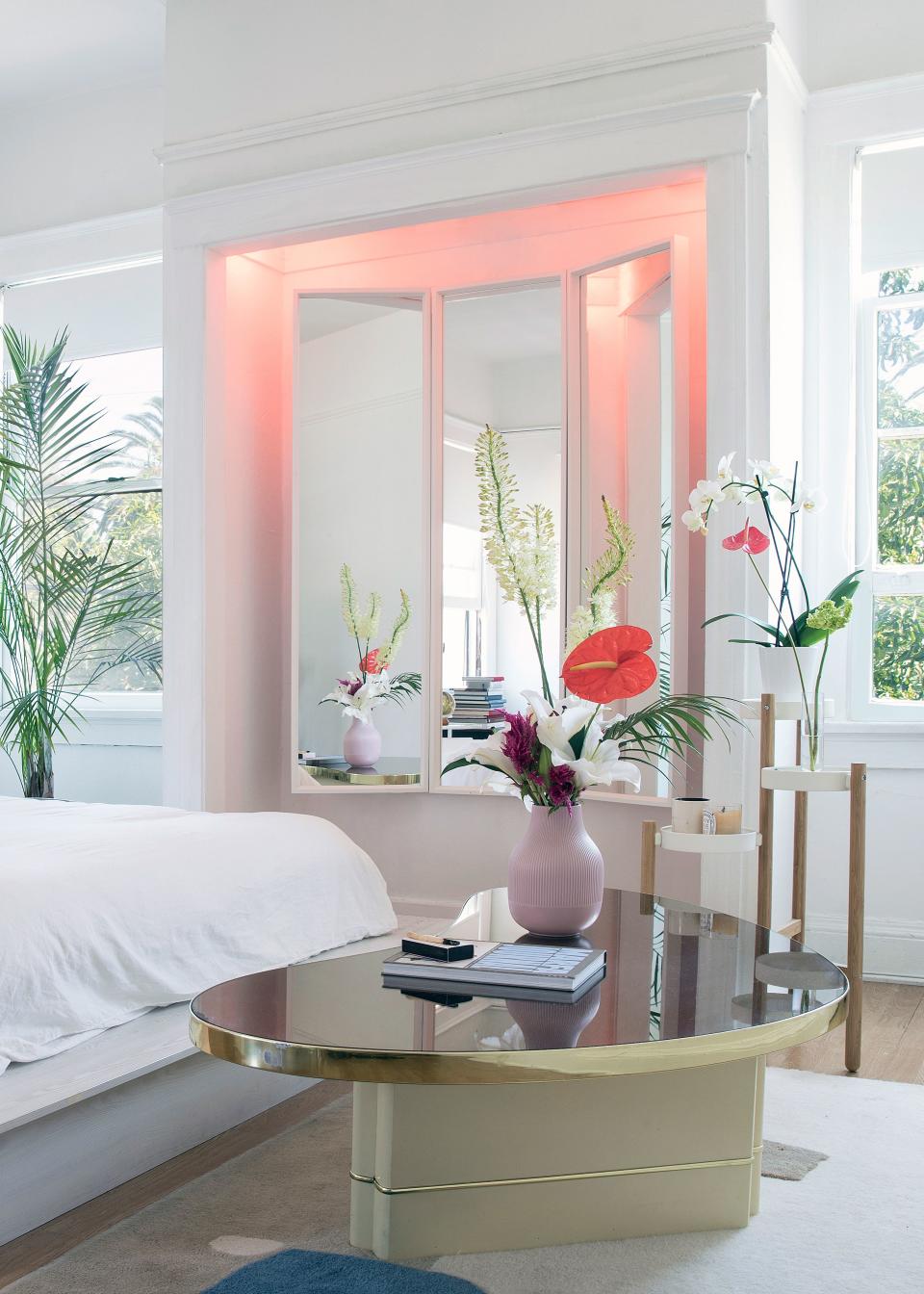Colored light bulbs cast a bright pink glow on an awkwardly sized nook, once used for a Murphy bed. “The triptych mirror fit perfectly," Hannah says.