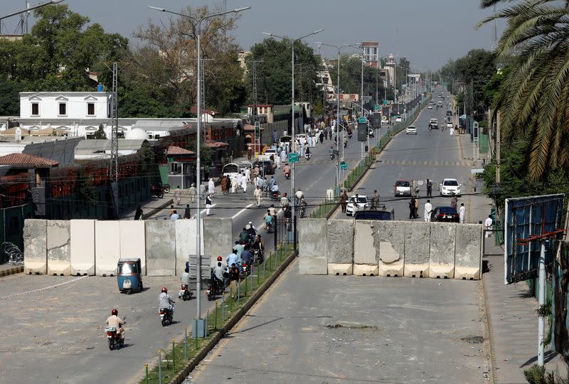 Motorcyclists move through a barricaded road following the arrest of Pakistan's former PM Khan, in Peshawar