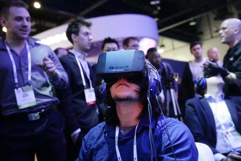 FILE - In this Jan. 7, 2014 file photo, show attendees play a video game wearing Oculus Rift virtual reality headsets at the Intel booth at the International Consumer Electronics Show(CES), in Las Vegas. Filmmaker Danfung Dennis' latest project: a virtual reality documentary, "Zero Point," will be the first movie released for the Oculus Rift, a VR headset that provides an immersive 110-degree field of view with high-definition stereoscopic 3D and low-latency head tracking. (AP Photo/Jae C. Hong, File)