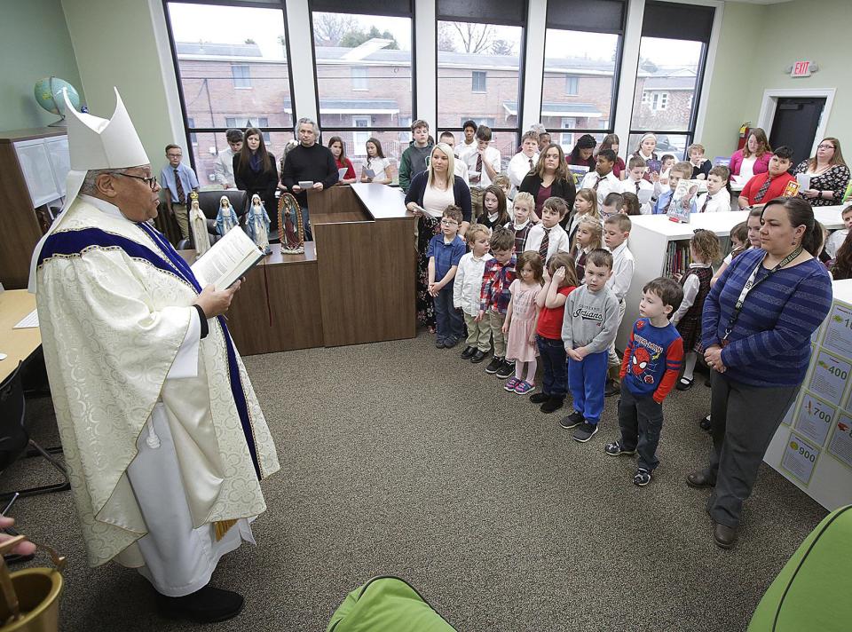 Bishop George V. Murry, the late spiritual leader of the Catholic Diocese of Youngstown, reads a blessing at the new Holy Cross Academy St. Barbara campus library after its remodeling.