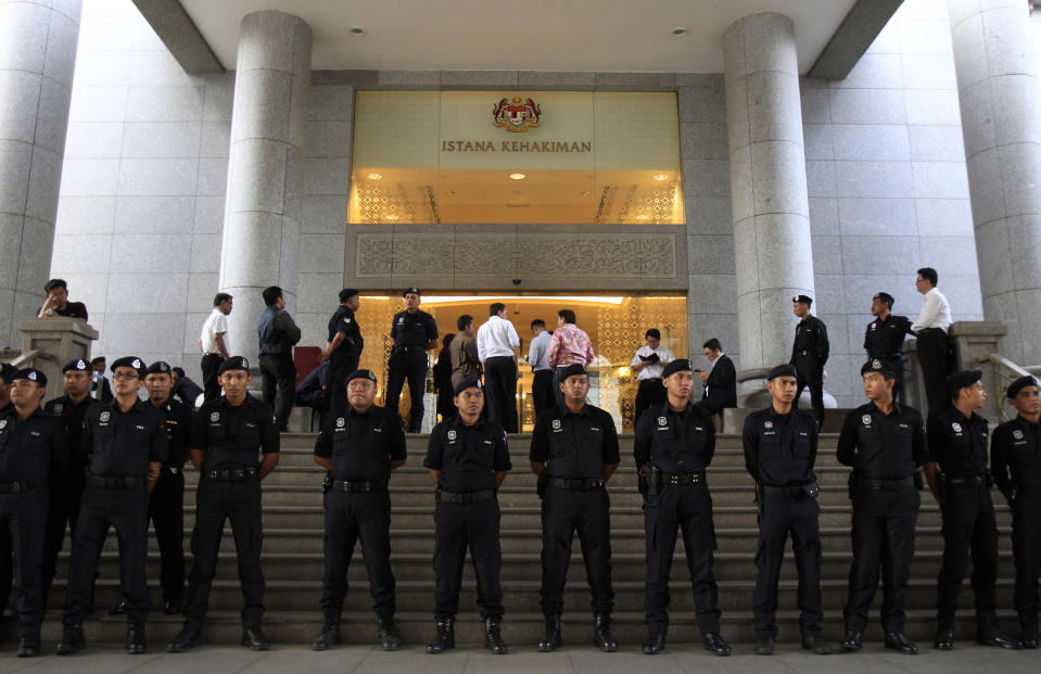 Malaysian police officers stand guard outisde a courthouse in Putrajaya, Malaysia, Friday, March 7, 2014. A Malaysian court Friday found Malaysian opposition leader Anwar Ibrahim guilty on sodomy charges, overturning an earlier acquittal and dealing a major blow to his hopes of contesting a local election this month. (AP Photo/Lai Seng Sin)