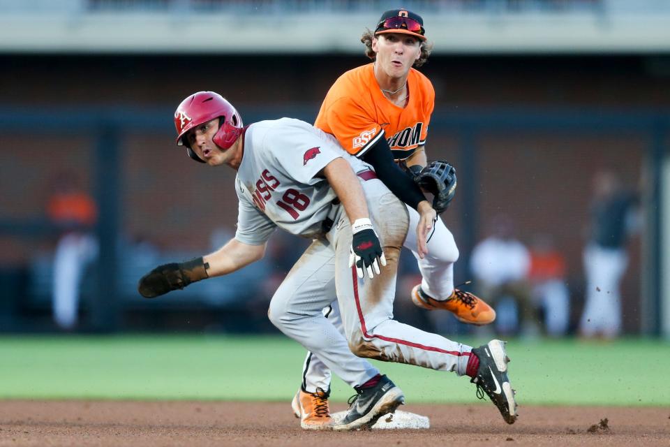 Arkansas infielder Chris Lanzilli (18) collides with Oklahoma State infielder Marcus Brown (19) after Brown throws to first base to turn a double play during an NCAA college baseball tournament regional game in Stillwater, Okla., on Monday, June 6, 2022.