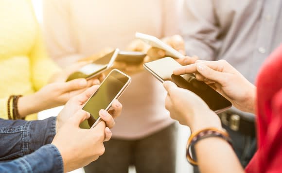 A group of people play with their smartphones.