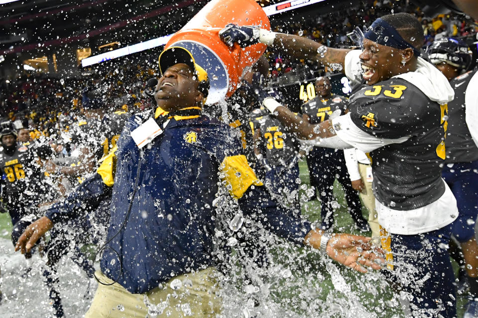 FILE - In this Dec. 21, 2019, file photo, North Carolina A&T coach Sam Washington is doused by defensive back Jalon Bethea during the final seconds of the Celebration Bowl NCAA college football game against Alcorn State, in Atlanta. Teams in the SWAC as well as many other HBCUs across the country play in the Football Championship Subdivision (FCS). Schools at this level earn some money from television contracts, but nothing like the multimillion-dollar deals for the Power Five. In the SWAC, the main source of revenue from football comes from putting fans in the stands and there are no substitutes for that at schools that often have limited resources. (John Amis/Atlanta Journal-Constitution via AP, File)