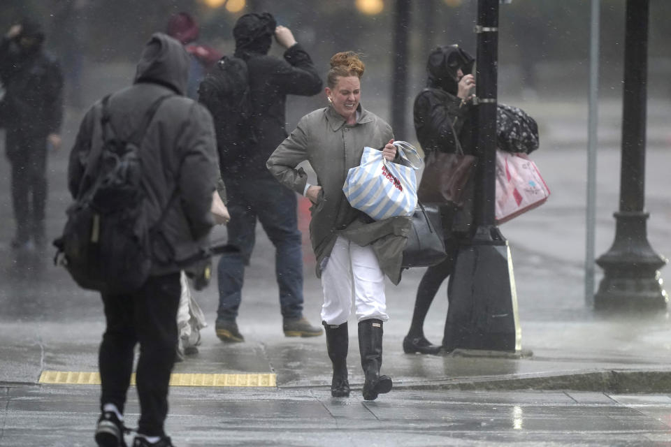Pedestrians are buffeted by wind and rain as they cross a street, Monday, Dec. 18, 2023, in Boston. A storm moving up the East Coast brought heavy rain and high winds to the Northeast on Monday, threatening flooding, knocking out power to hundreds of thousands. (AP Photo/Steven Senne)