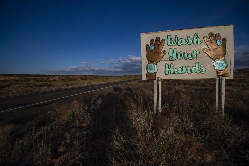 A sign on Highway 98 featuring Navajo turquoise jewelry reads "Wash Your Hands"