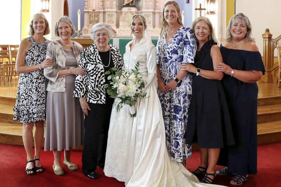 Bride Serena Stoneberg, center, stands with six women in her family who have all worn the same wedding dress, at Ebenezer Lutheran Church in Chicago’s Andersonville neighborhood on Aug. 5, 2022, at Stoneberg's wedding. From left are Susan Stoneberg McCarthy, married in 1982; Sharon Larson Frank, married in 1969; Eleanor Larson Milton, married in 1953; Stoneberg Lipari, Julie Frank Mackey, married in 2013; Jean Milton Ellis, married in 1991; and Carol Milton Zmuda, married in 1990. Not pictured is Adele Larson Stoneberg, married in the dress in 1950, who died in 1988.