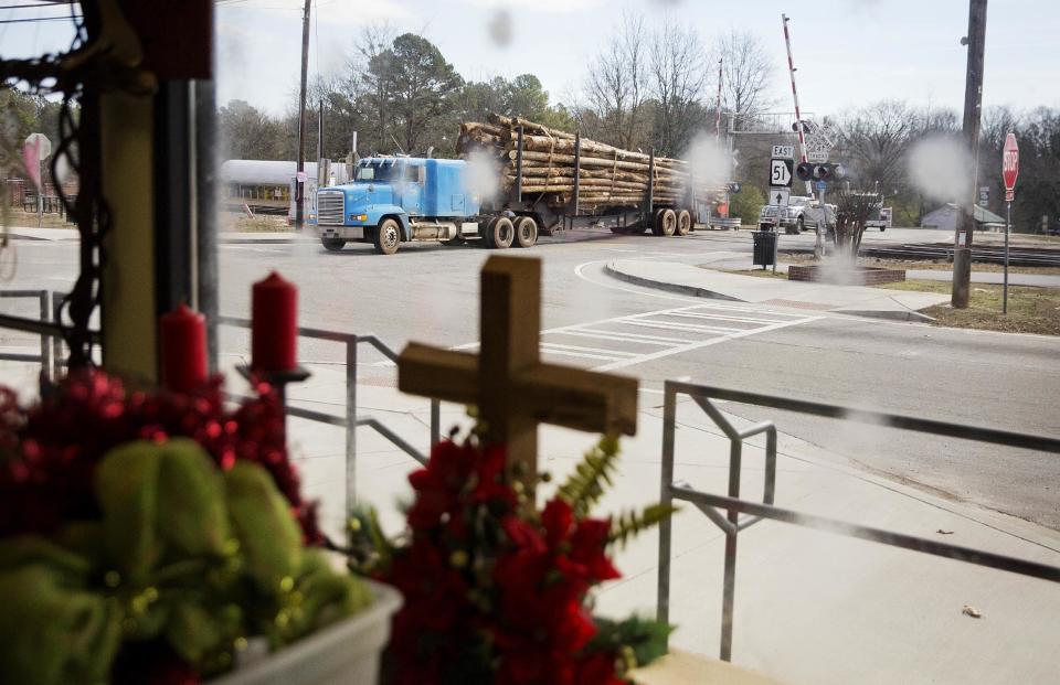 A logging truck passes through the Main Street business district as a cross stands in a flower shop window in Lula, Ga., in Hall County, Tuesday, Jan. 10, 2017. "This is Trump country up here," explains Margaret Luther, who works part-time at the flower shop, festooned with fresh and artificial flowers, Christian crosses and a wreath celebrating the University of Georgia Bulldogs. (AP Photo/David Goldman)