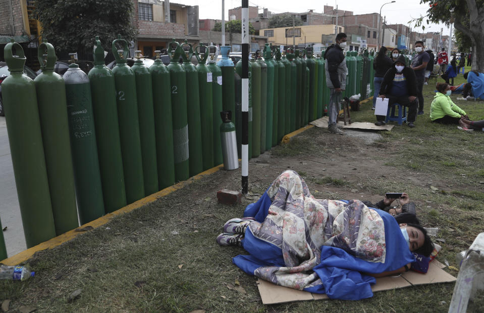 People lay next to their empty oxygen tanks as many wait for the refill shop to open in Callao, Peru, Monday, Jan. 25, 2021, amid the COVID-19 pandemic. A crisis over the supply of medical oxygen for coronavirus patients has struck nations in Africa and Latin America, where warnings went unheeded at the start of the pandemic and doctors say the shortage has led to unnecessary deaths. (AP Photo/Martin Mejia)