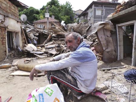 A man sits in front of debris after heavy floods in Varna June 21, 2014. . REUTERS/Impact Press Group