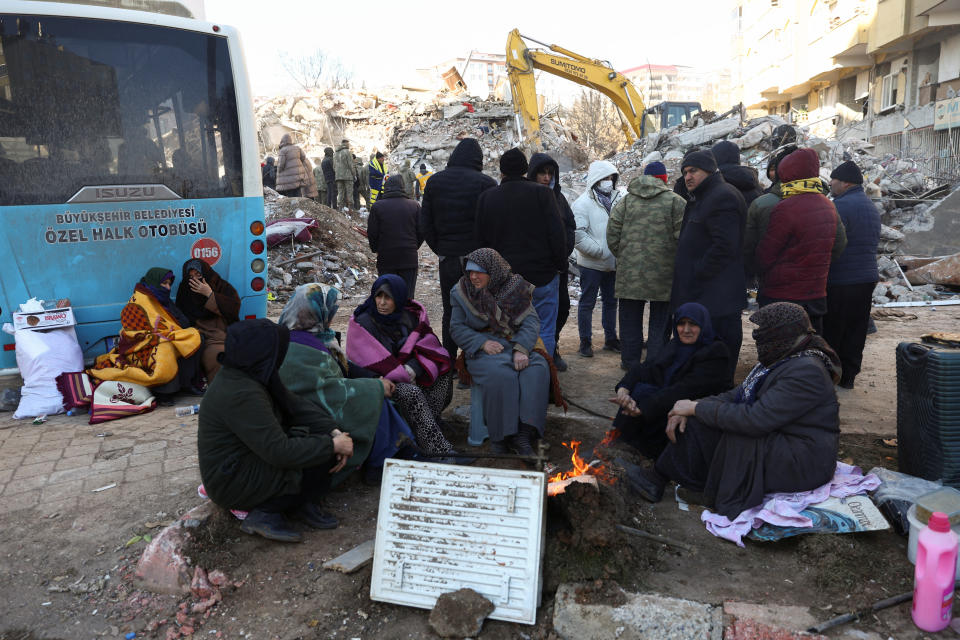 People gather around a fire near the site of a collapsed building, in the aftermath of the deadly earthquake, in Kahramanmaras, Turkey, February 8, 2023. REUTERS/Ronen Zvulun