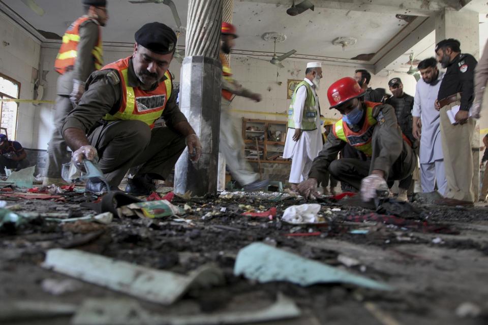 Rescue workers and police officers examine the site of the bomb explosion in an Islamic seminary in Peshawar: AP