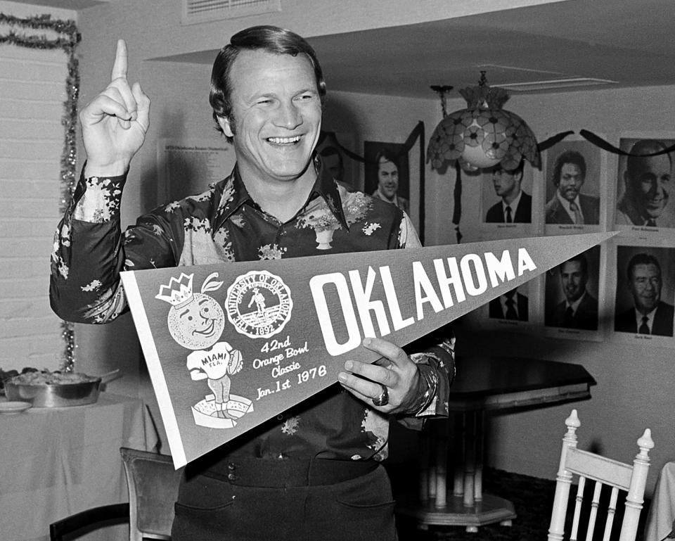 FILE - Oklahoma football coach Barry Switzer, who holds a pennant and indicates his Sooners are No. 1, celebrates after defeating Michigan in the Orange Bowl game in Miami Beach, Jan. 2, 1976. Oklahoma and Oklahoma State will meet on Saturday for the final time before Oklahoma leaves the Big 12 for the Southeastern Conference. (AP Photo/File)