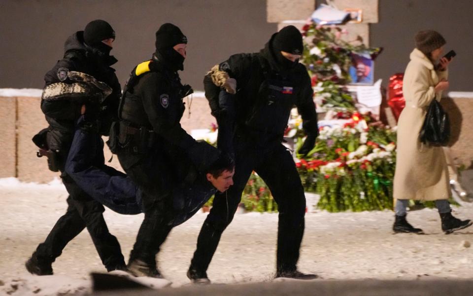 Police officers detain a man laying flowers to Alexei Navalny at the Memorial to Victims of Political Repression in St. Petersburg, Russia on Friday, Feb. 16, 2024.