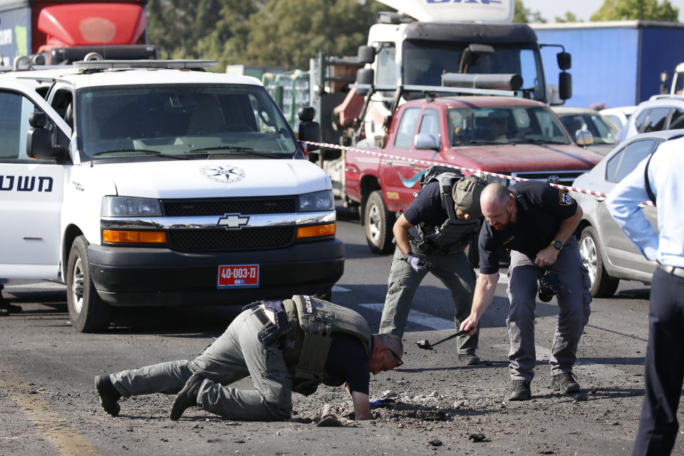 Israeli police officers examine the site moments after a rocket fired by Palestinians militants from Gaza hit a main free way between Ashdod and Tel Aviv near Ashdod Israel, Tuesday, Nov. 12, 2019. Israel has killed a senior Islamic Jihad commander in Gaza in a rare targeted killing that threatened to unleash a fierce round of cross-border violence with Palestinian militants. (AP Photo/Ariel Schalit)