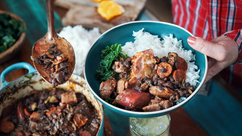 Person dishing up feijoada with rice