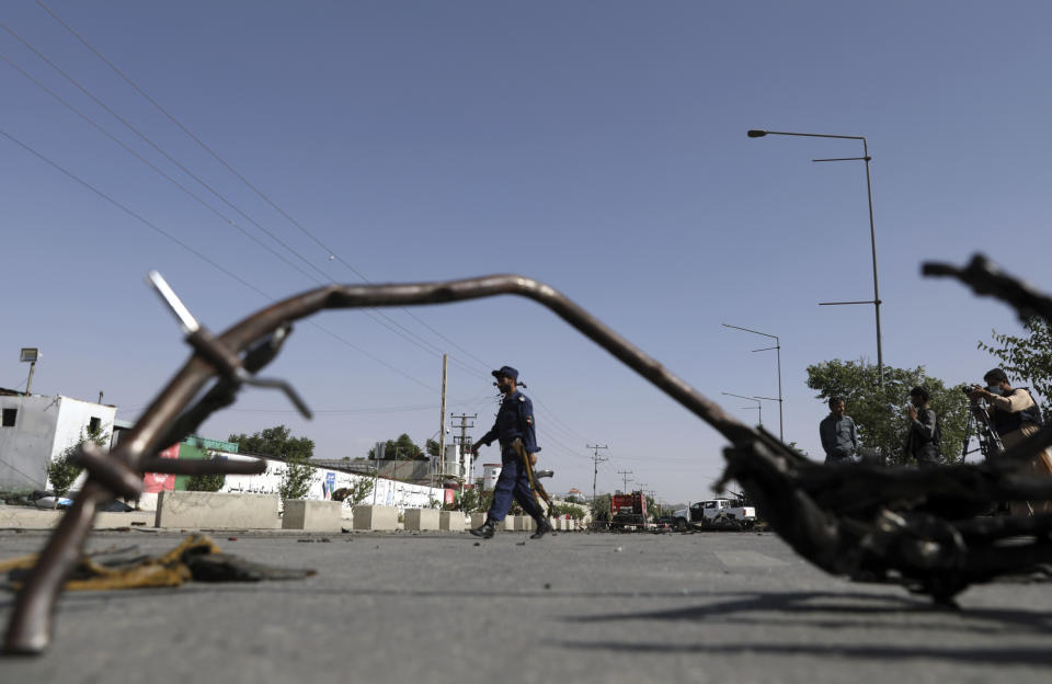 Afghan security personnel inspect the site of a bomb explosion in Kabul, Afghanistan, Thursday, June 3, 2021. Police say a bomb has ripped through a minivan in the western part of the Afghan capital Kabul, killing at least four people. No one took responsibility for the attack in the neighborhood, which is largely populated by the minority Hazara ethnic group who are mostly Shiite Muslims. (AP Photo/Rahmat Gul)