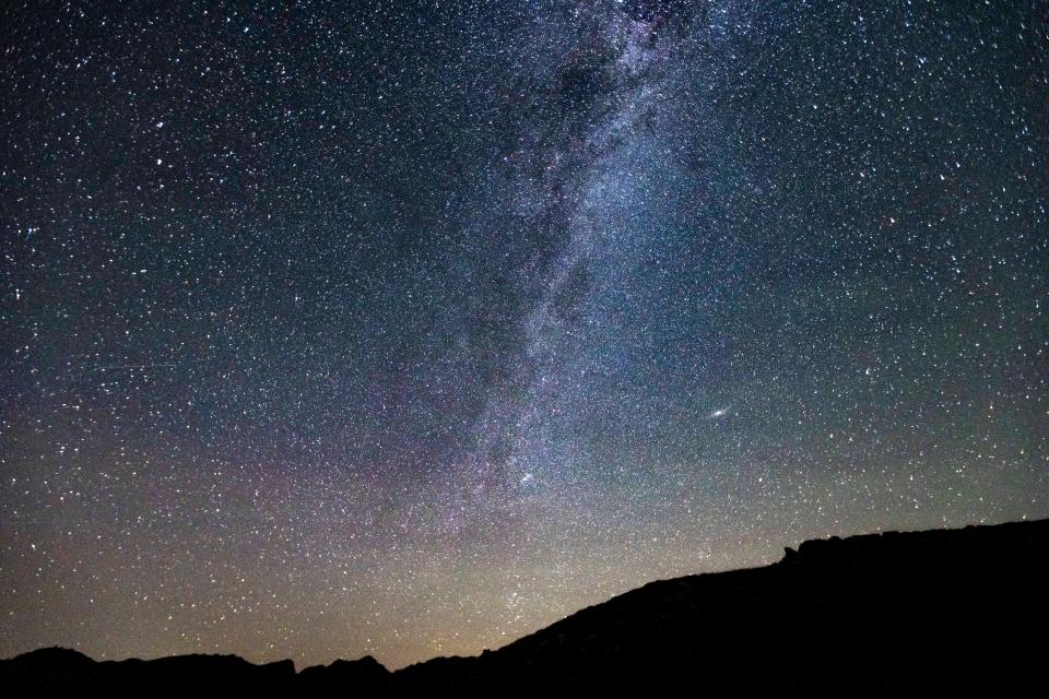 Milky Way captured with long exposure photography technique. Milkyway is the visible part of our galaxy that contains our Solar System as seen during the dark night sky from Tymfi Mountain in Pindos Range in Epirus. Night landscape over the mountain with colorful Milky Way sky dome, the cloudless sky at mountains with the starry sky with hills at summer with the beautiful Universe and Space background. Timfi Mountain, Pindus, Greece on July 2022