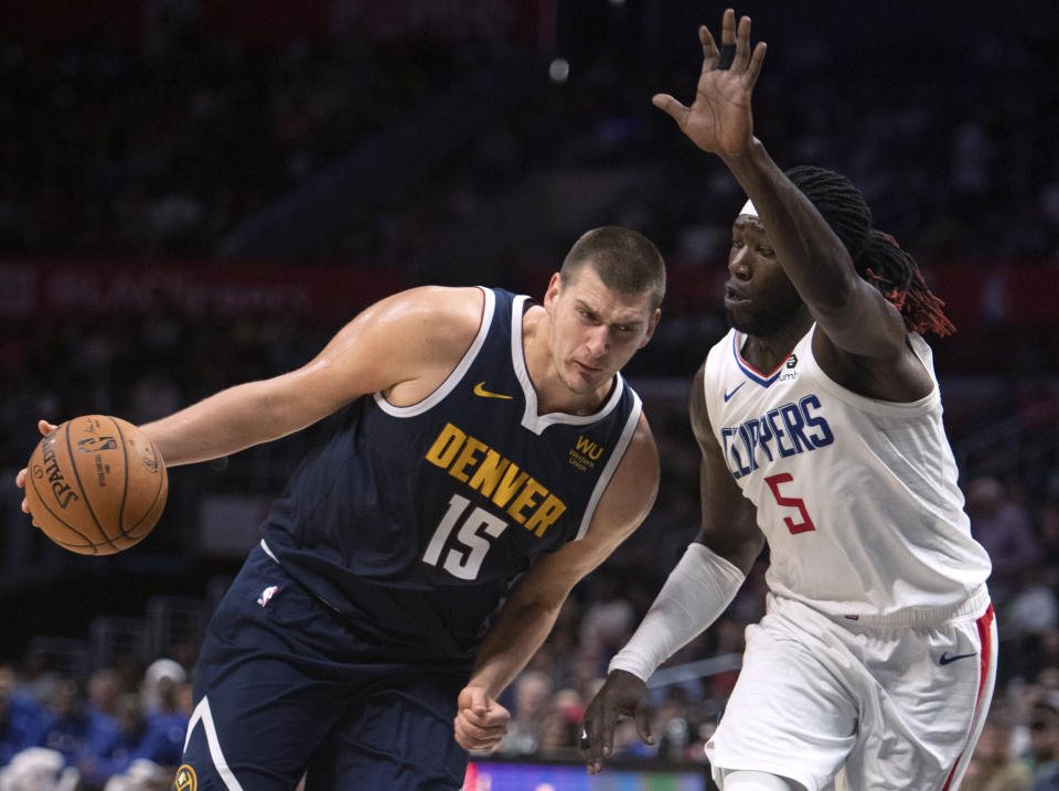 Denver Nuggets center Nikola Jokic, left, drives toward the basket as Los Angeles Clippers forward Montrezl Harrell defends during the first half of an NBA preseason basketball game in Los Angeles on Thursday, Oct. 10, 2019. (AP Photo/Kyusung Gong)