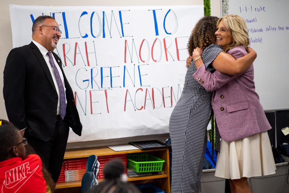 First lady Jill Biden hugs third grade teacher Kaitlyn Baker as Education Secretary Miguel Cardona watches on at Sarah Moore Greene Magnet Academy.