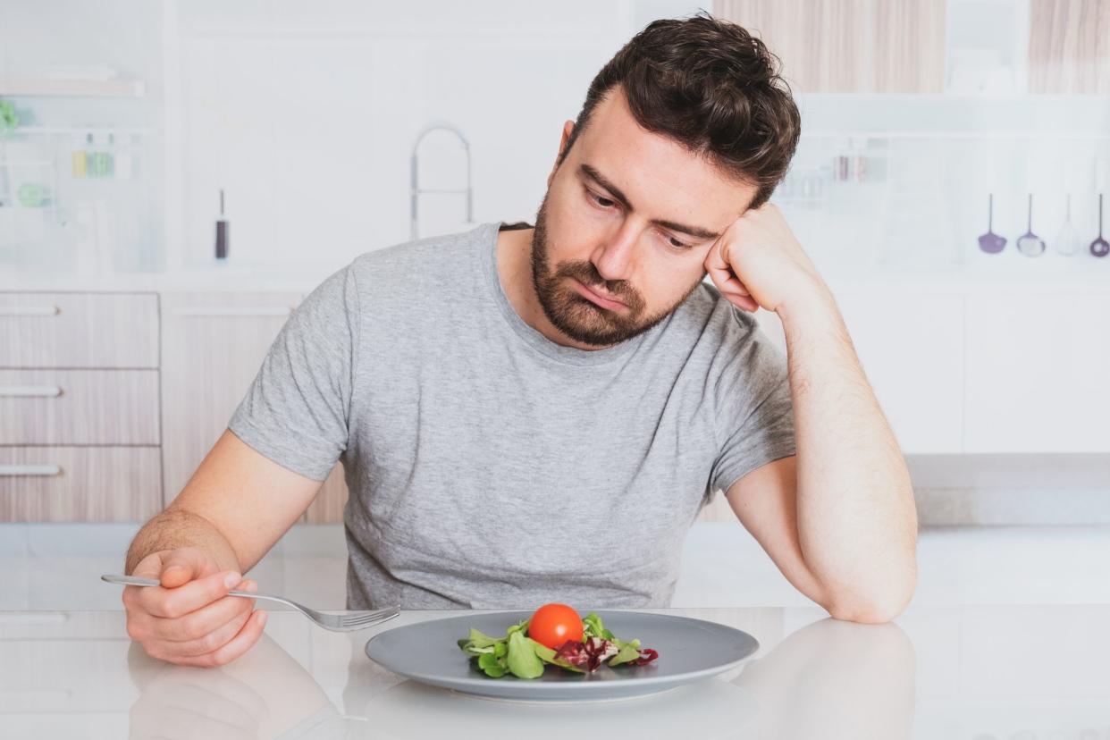 Worried man hungry and starved with salad