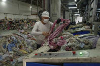 A worker feeds discarded textiles to a shredding machine at the Wenzhou Tiancheng Textile Company, one of China's largest cotton recycling plants in Wenzhou in eastern China's Zhejiang province on March 20, 2024. The recycling factory that repurposes discarded cotton clothes is trying to deal with the urgent waste problem. (AP Photo/Ng Han Guan)